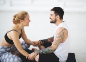 Young woman and man talking after yoga classes while smiling