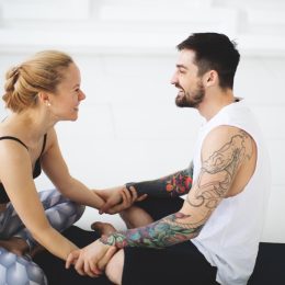 Young woman and man talking after yoga classes while smiling