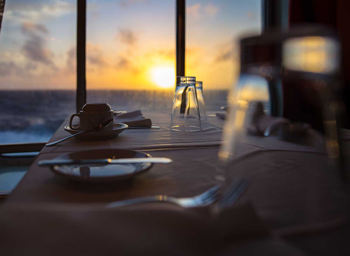 dinner table on a cruise with sunset in background