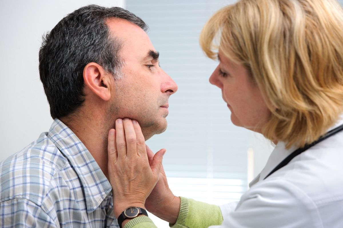 female doctor touching the throat of a patient in the office