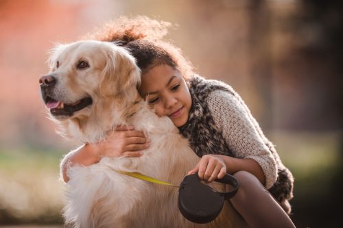 little girl hugging golden retriever
