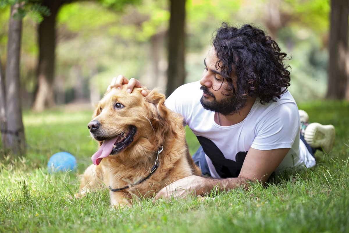 young man spending time with his Golden Retriever outdoors.
