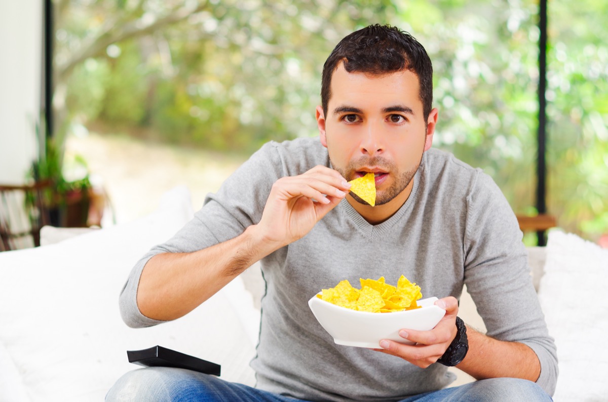 Man eating chips on couch