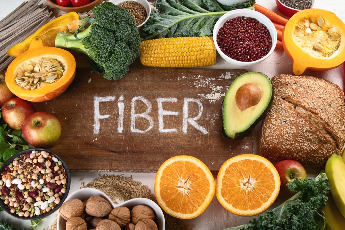 High in fiber foods surrounding the word "fiber" written in chalk on a wooden cutting board 