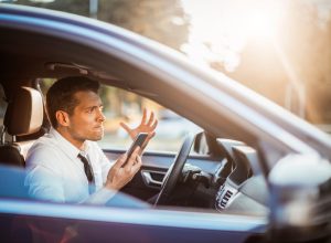 Close up photo of a businessman yelling at his phone while driving