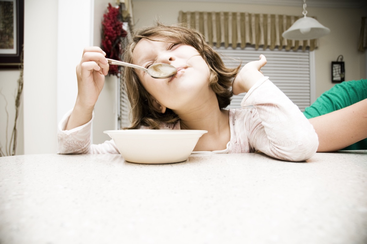Young girl eating cereal with her elbows on the table being sassy