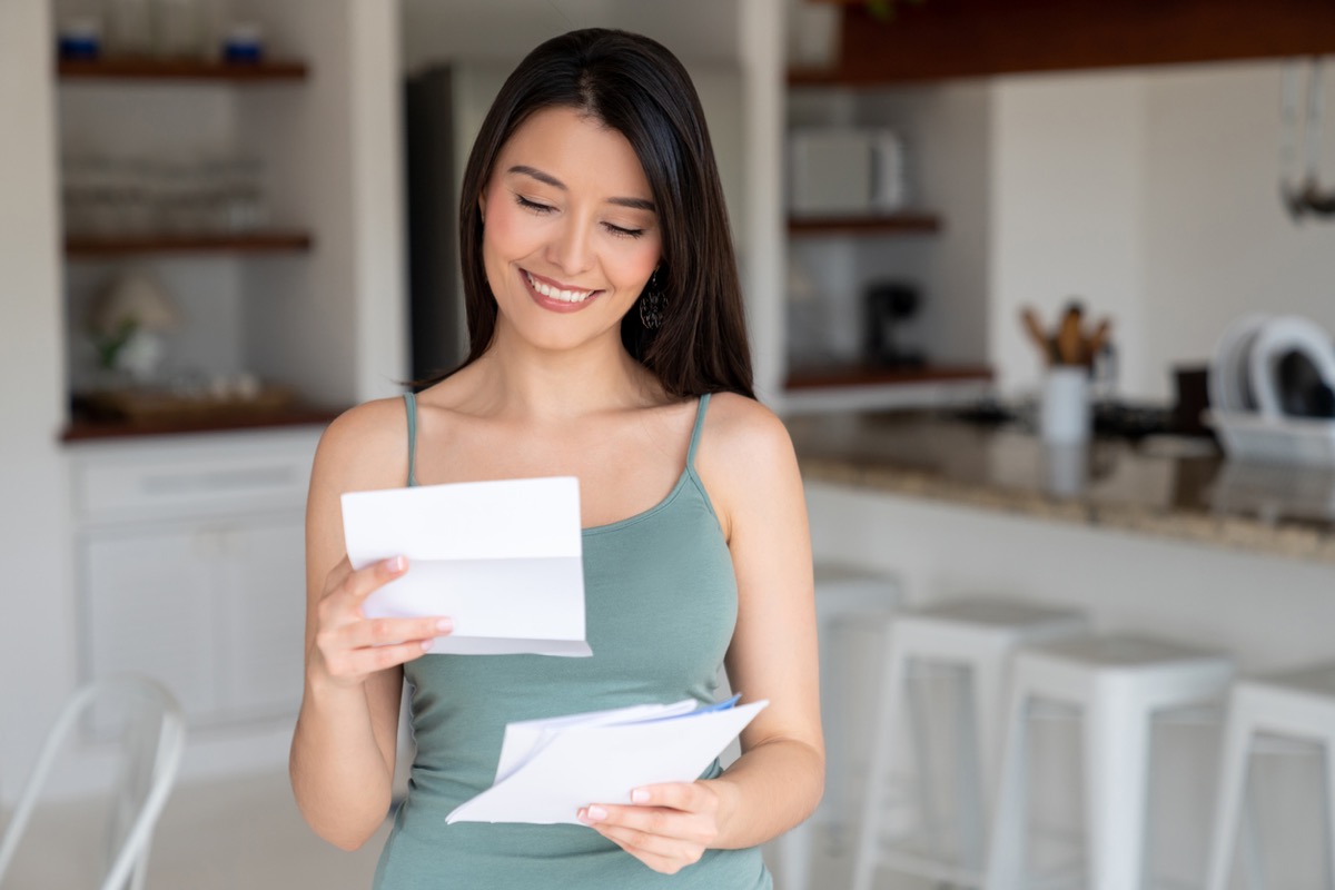 happy young hispanic woman reading letter