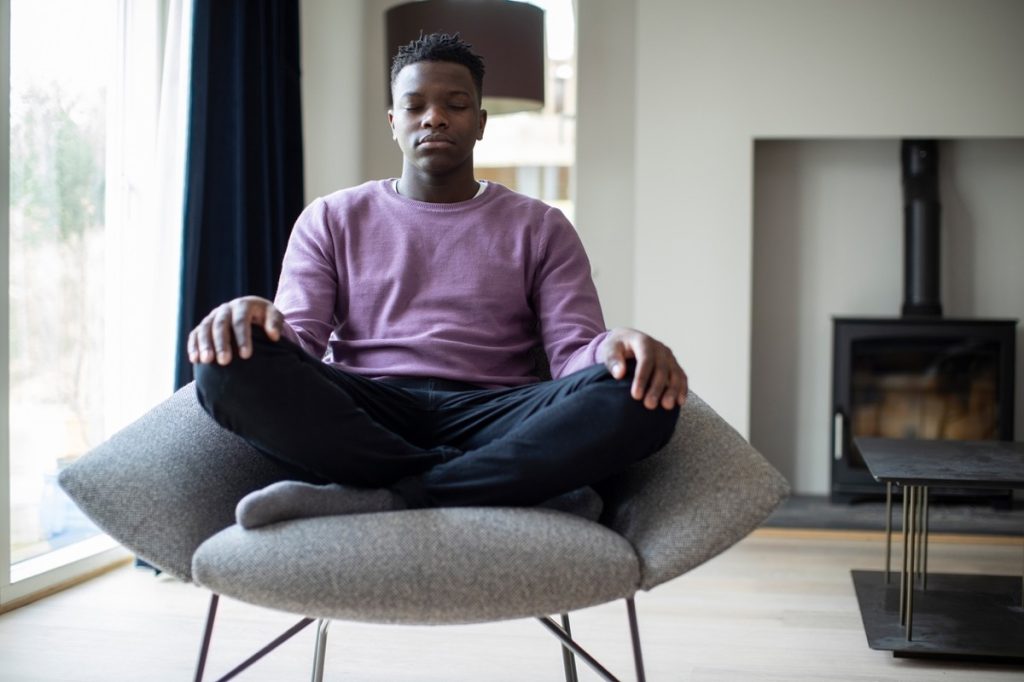 young black man meditating in a chair
