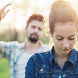 white woman looking sad with white man behind her throwing up his hand in anger