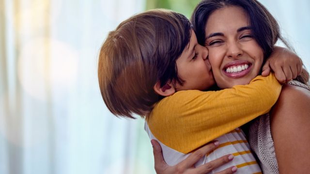 Shot of an adorable Latinx little boy affectionately kissing his mother at home while hugging her