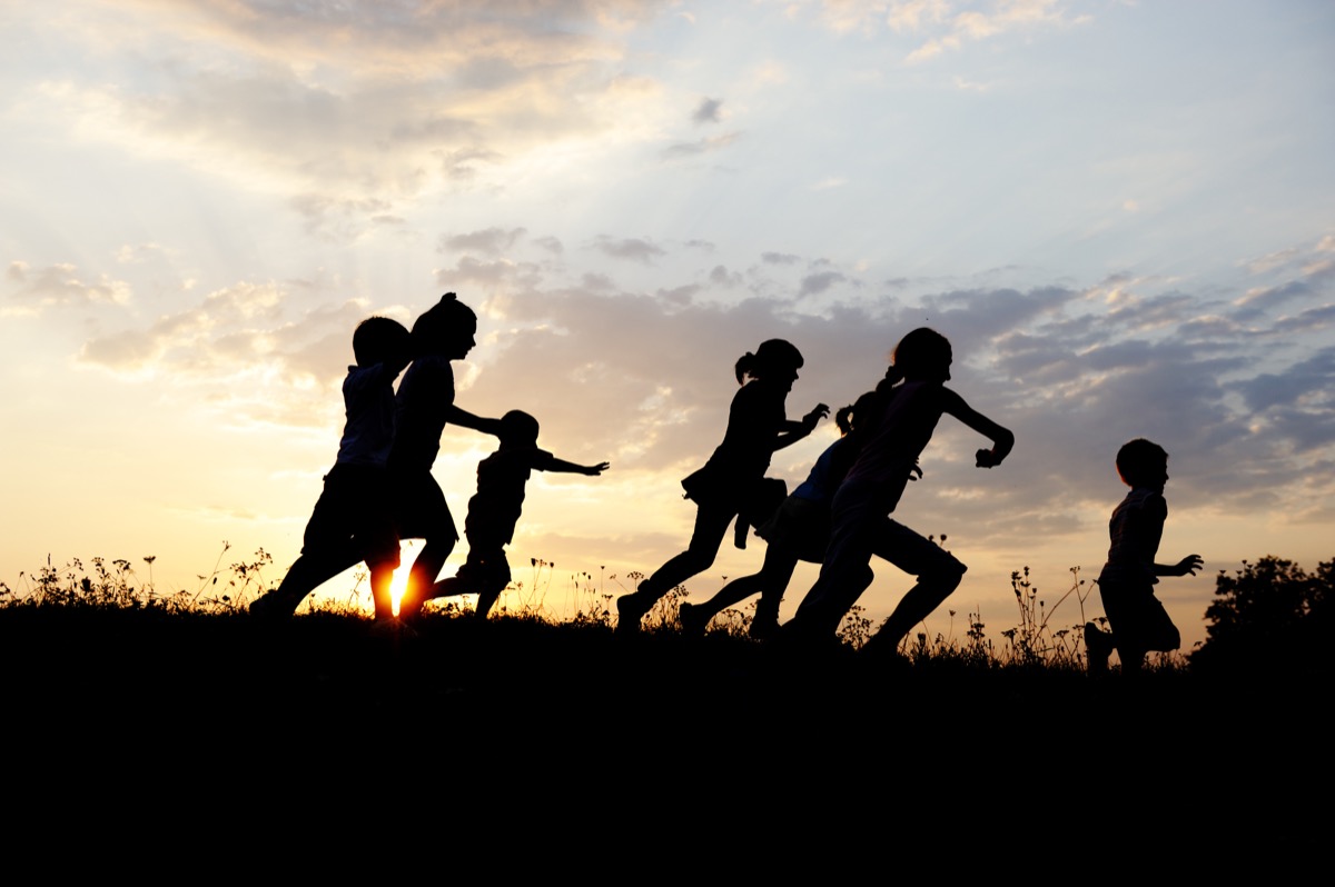 Kids running in a field at sunset