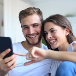 Couple looking and laughing at phone on couch