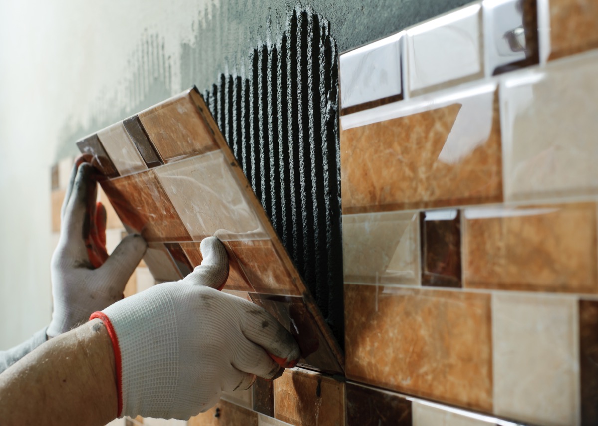 Man laying ceramic tile on the wall