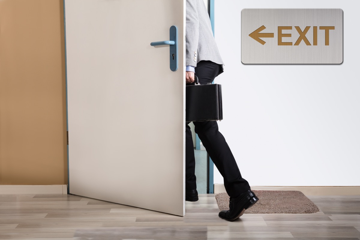 Business man leaving door with exit sign