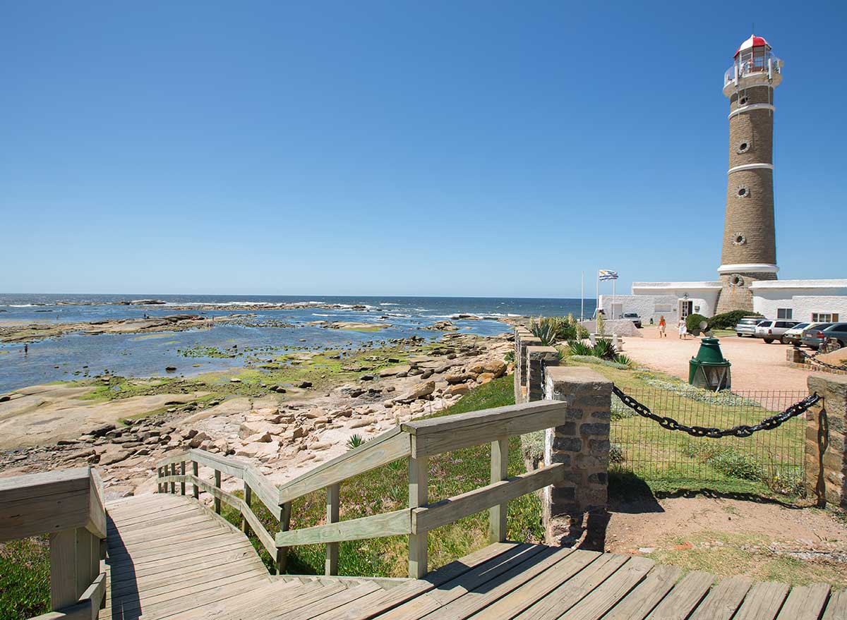 a boardwalk with steps to the beach and a lighthouse in the background