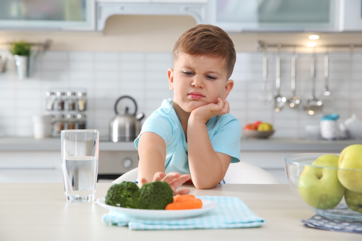Little boy refusing to eat vegetables broccoli and carrots