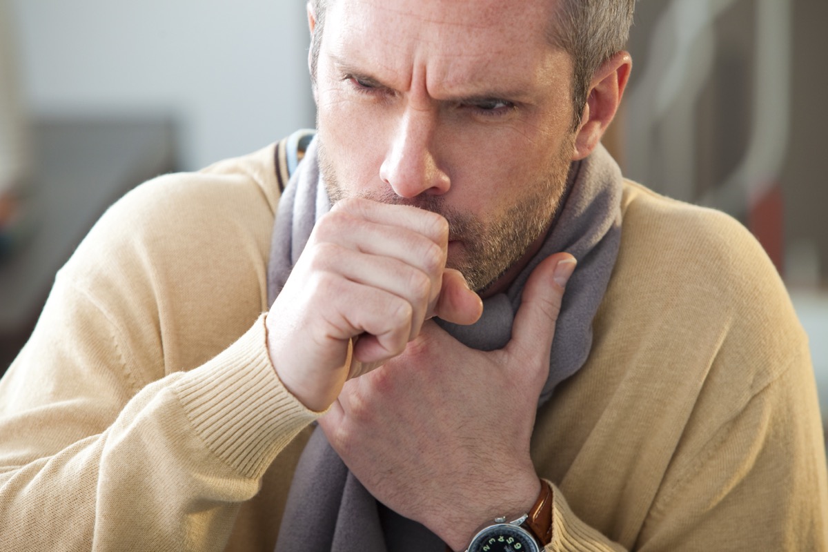 Man coughing wearing a scarf