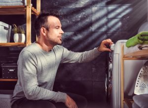 man looking at washing machine setting the presets