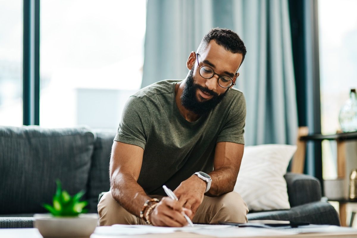 Shot of a young man going over his finances at home