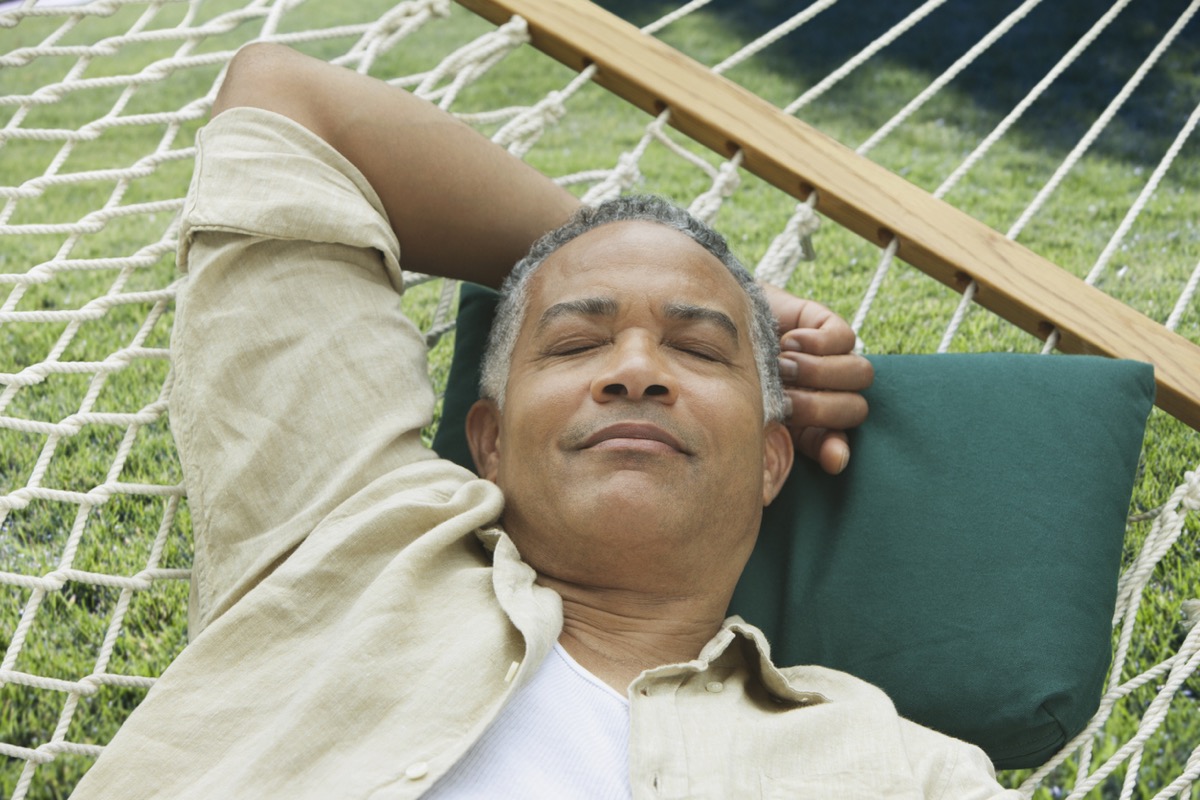 Older black man sleeping on a hammock