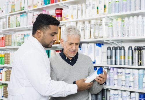Pharmacist helping senior man find shampoo in store