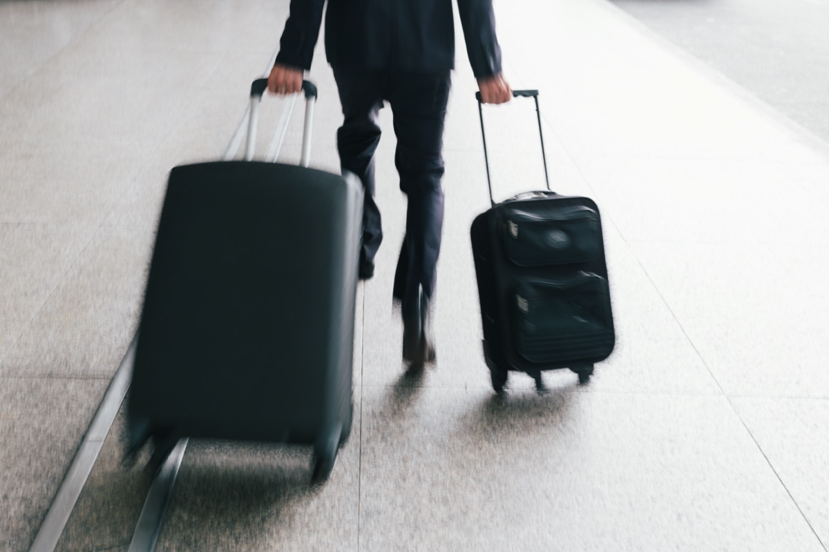 man running with two luggages
