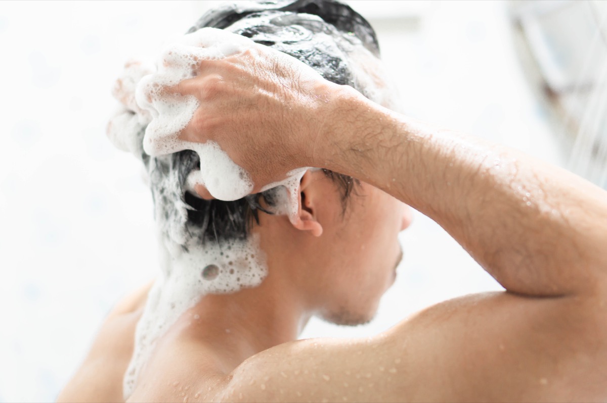 Man washing his hair with shampoo in the shower