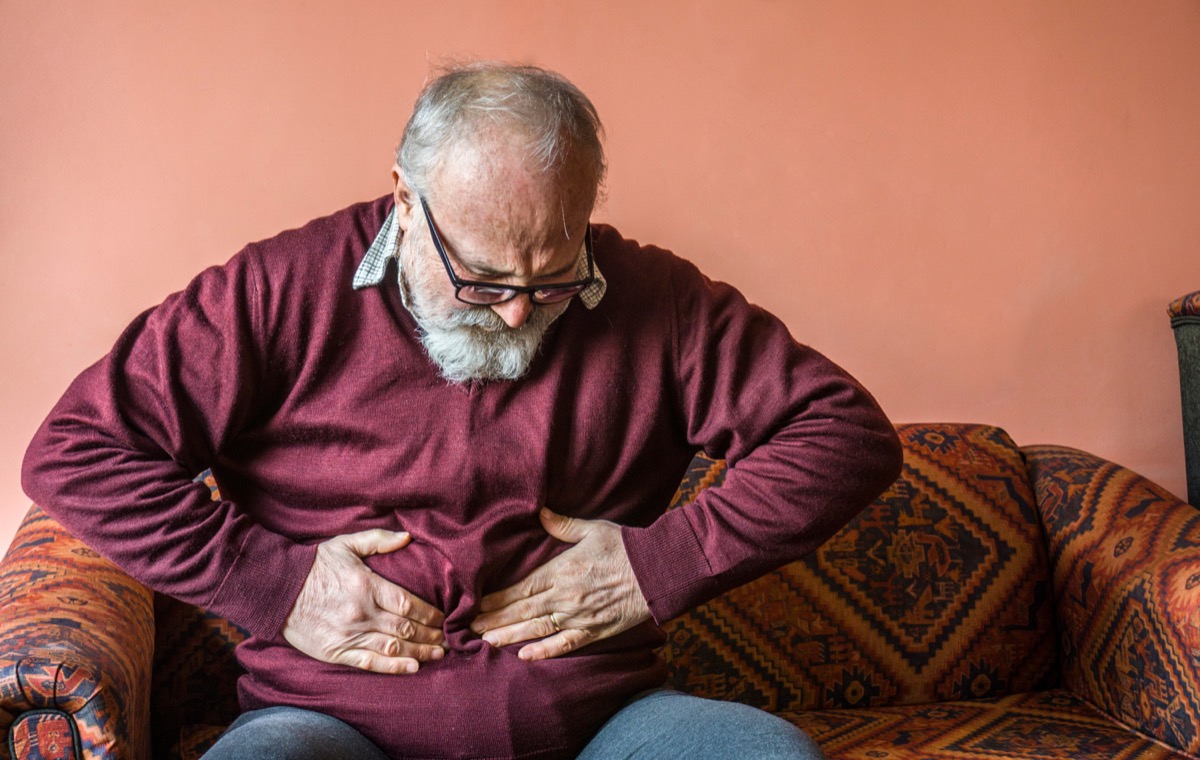 Older man toughing his swollen stomach in discmofort