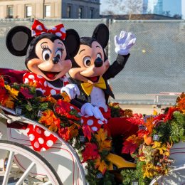 mickey and minnie in an open carriage during a disneyland parade