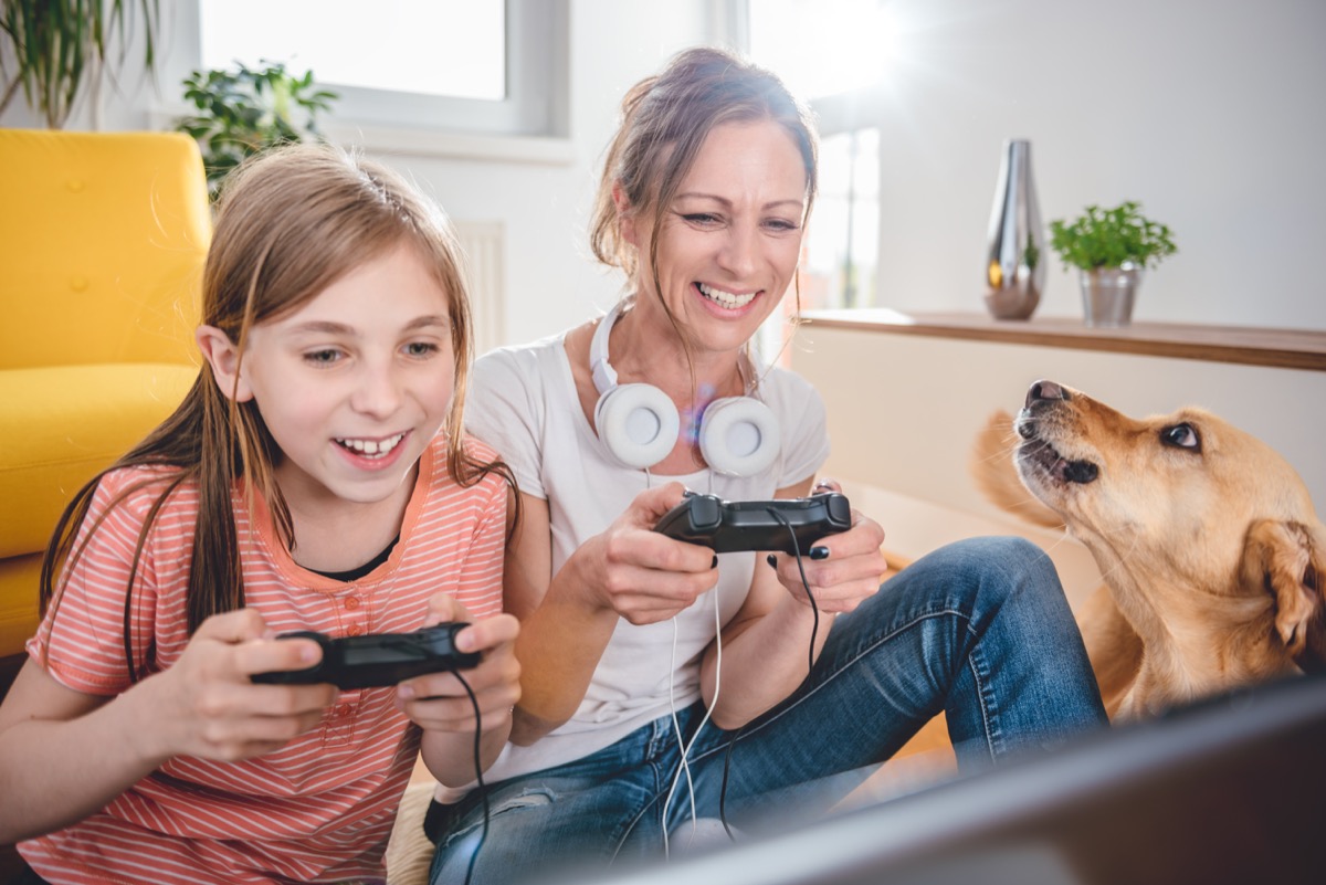 mother and daughter playing video game in front of dog