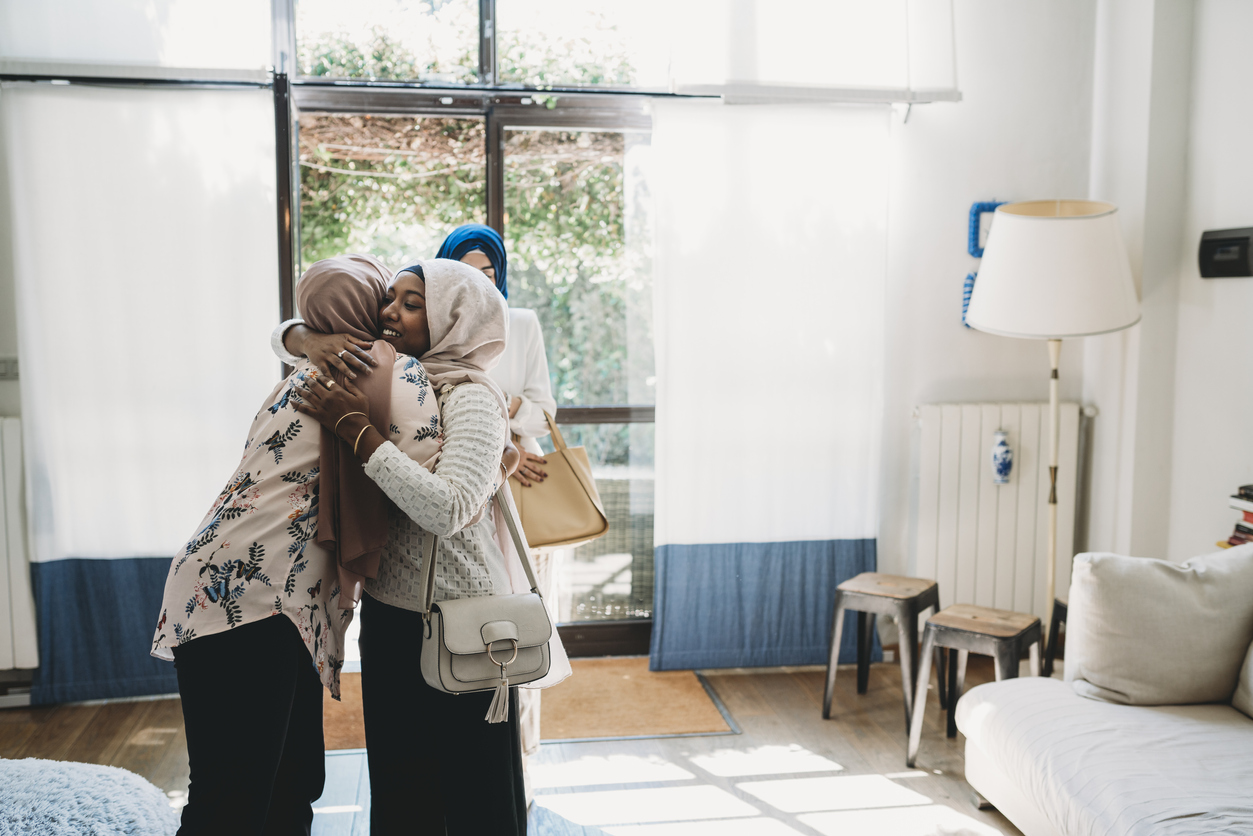 Young Muslim women hugging at home