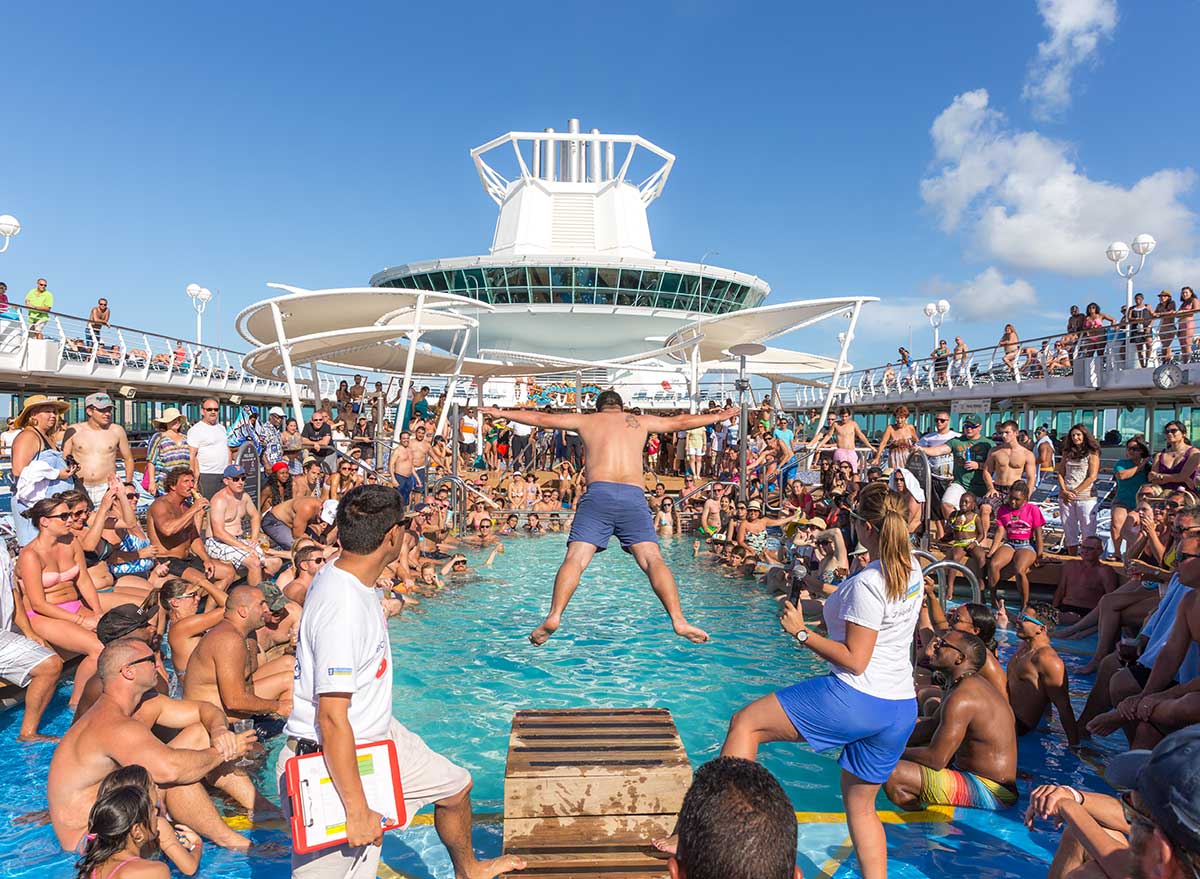 a crowded deck on a cruise ship with a man jumping in the pool