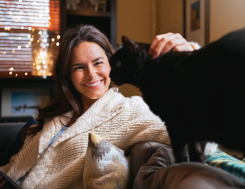 Shot of an attractive young woman relaxing on the sofa at home and bonding with her cat
