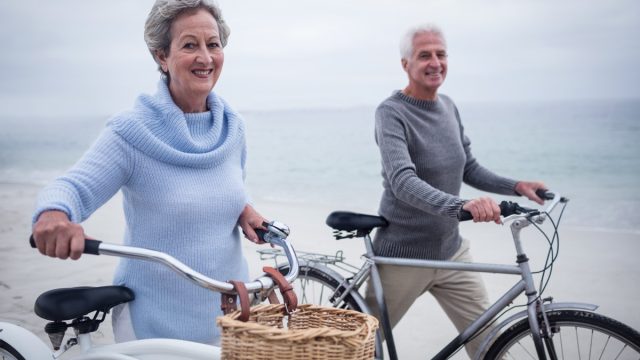 Older couple going for a bike ride on vacation near the beach