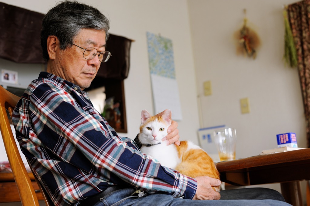 older man sitting at home with his cat.
