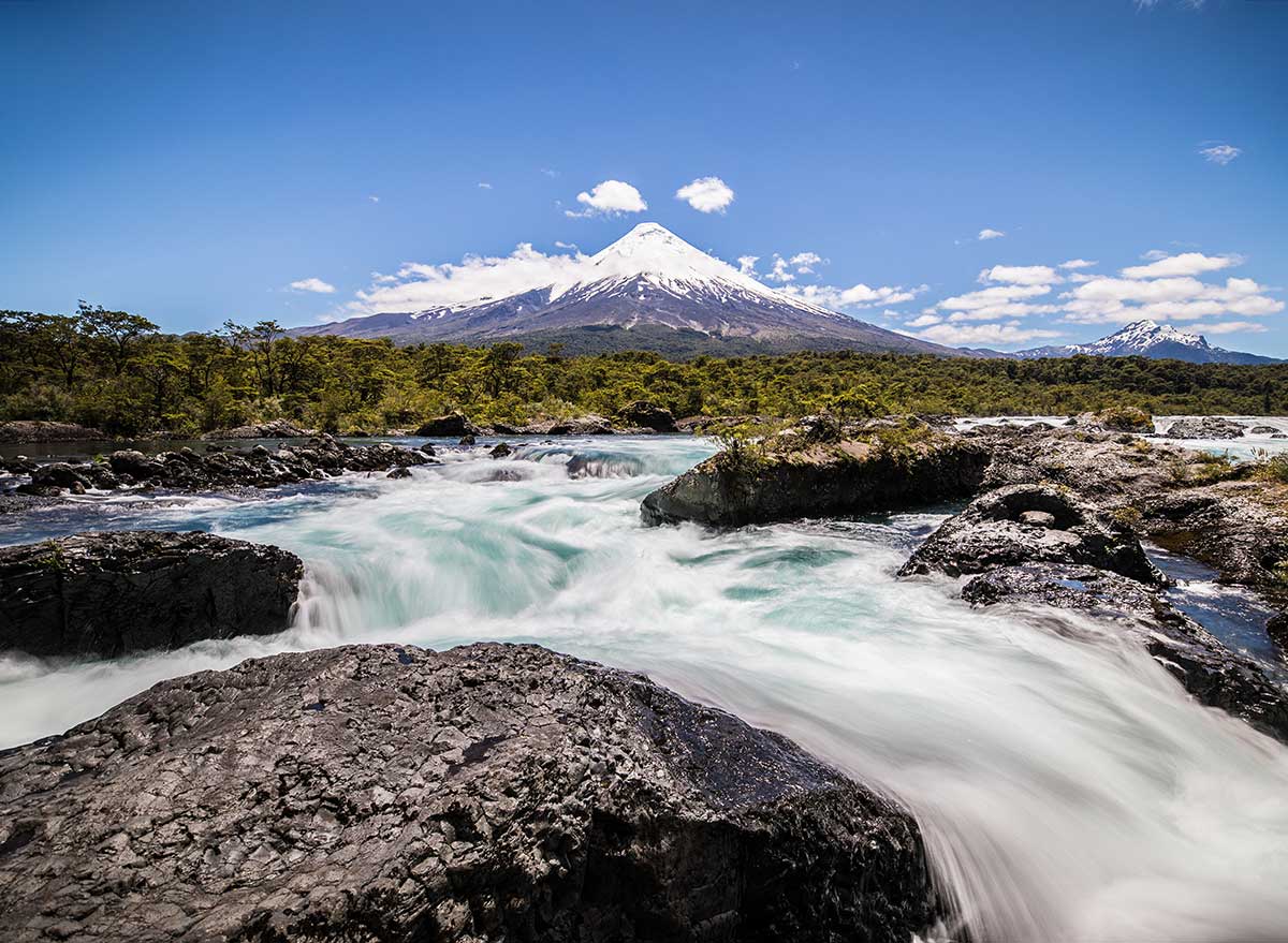 a rushing river with a mountain peak in the background