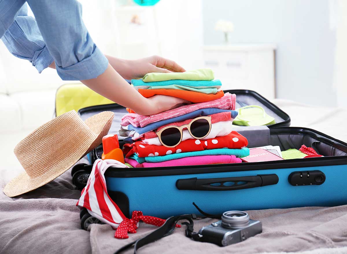 a suitcase piled hight with summer clothes