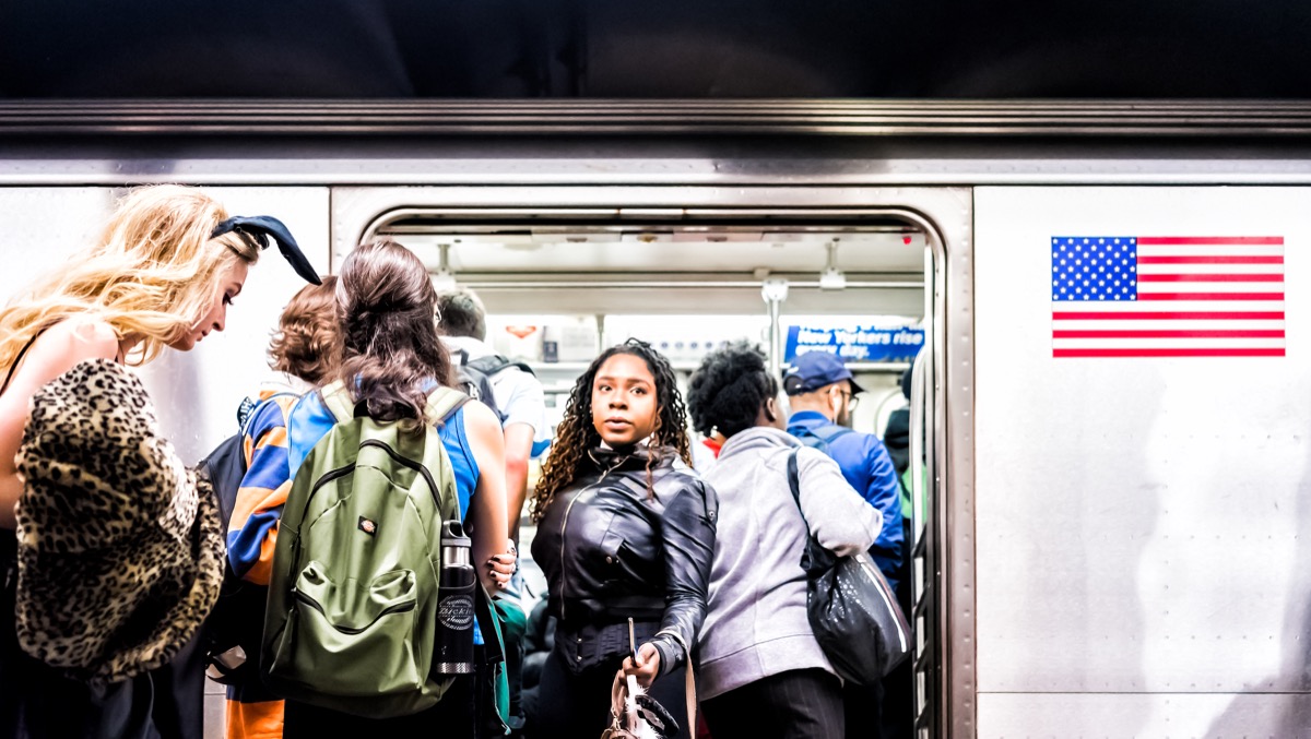 people in underground platform transit in NYC Subway Station on commute with train, people crammed crowd with open closing doors, woman exiting, boarding