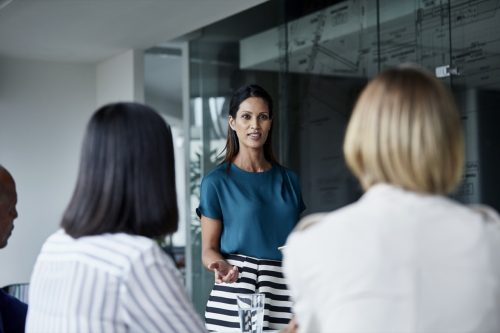 Young businesswoman discussing with team in meeting room