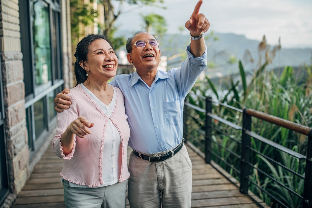man and woman, senior married couple standing on terrace at home together.