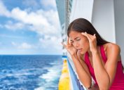 woman leans over cruise ship balcony seasick