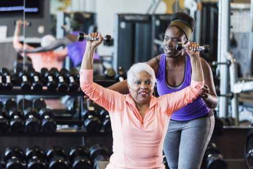 Afroamerikanischer Fitnesstrainer hilft einer älteren Frau