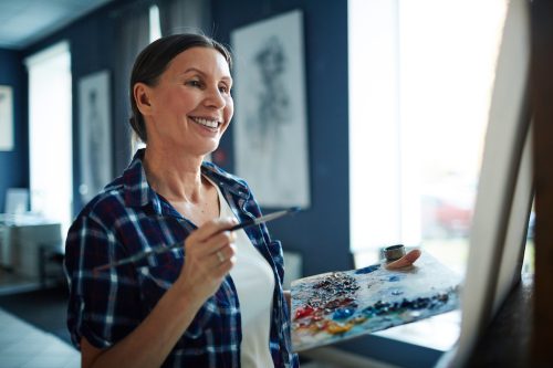 O femeie de cincizeci de ani pictează fericită