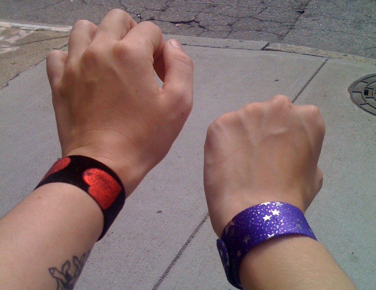 closeup of black slap bracelet with red hearts and purple slap bracelet with silver stars on wrists