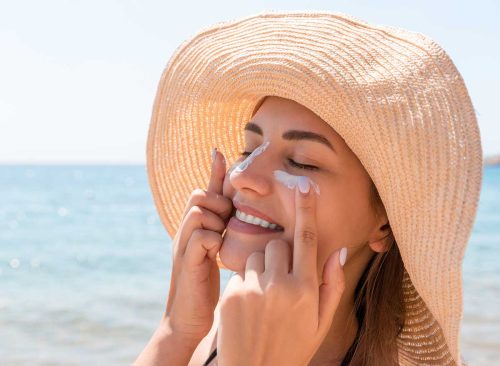 woman putting on sunscreen at the beach
