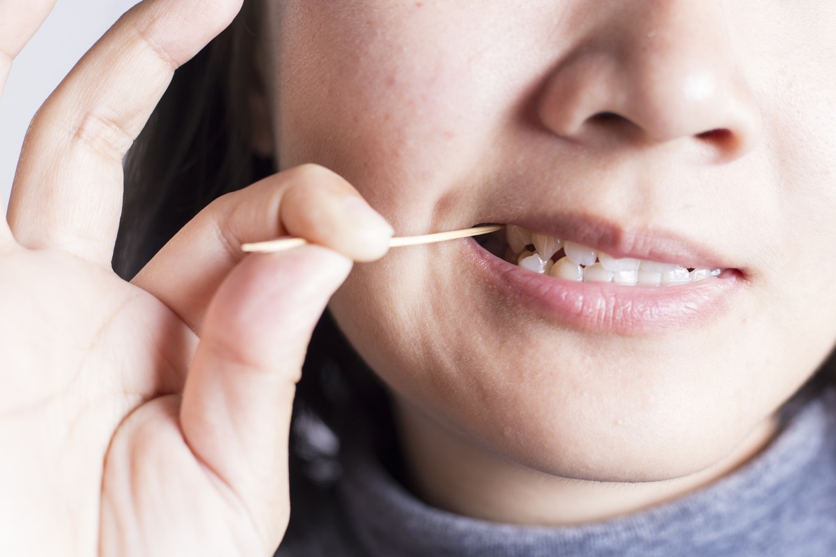 woman putting toothpick in her teeth
