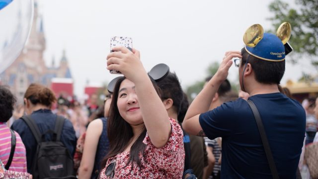 A young chinese woman is taking a selfie at Hong King Disneyland