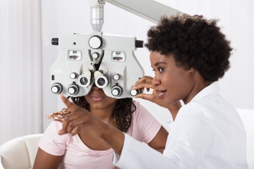 black woman doctor administering eye test to young patient