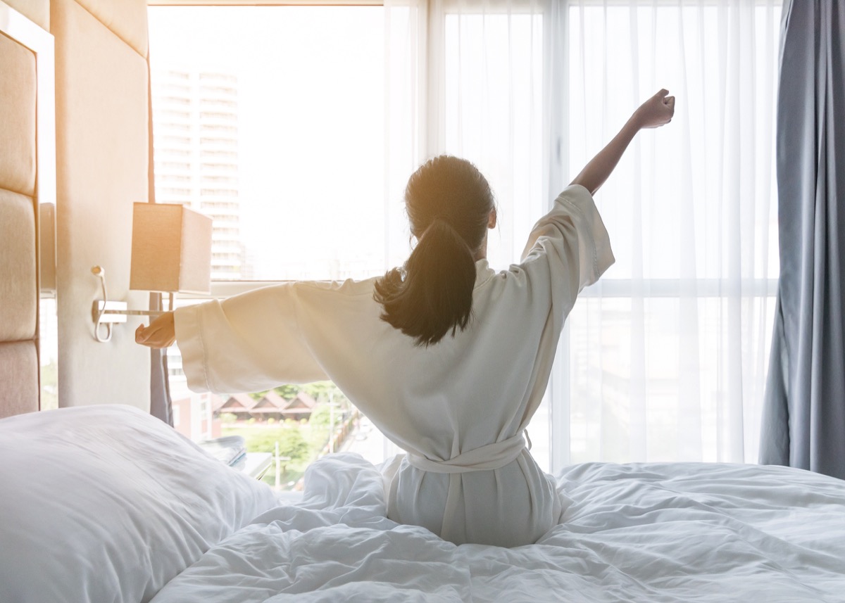 Woman stretching and waking up for the day in a hotel
