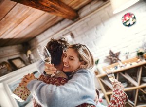30-something white woman hugging her boyfriend and holding a glass of champagne